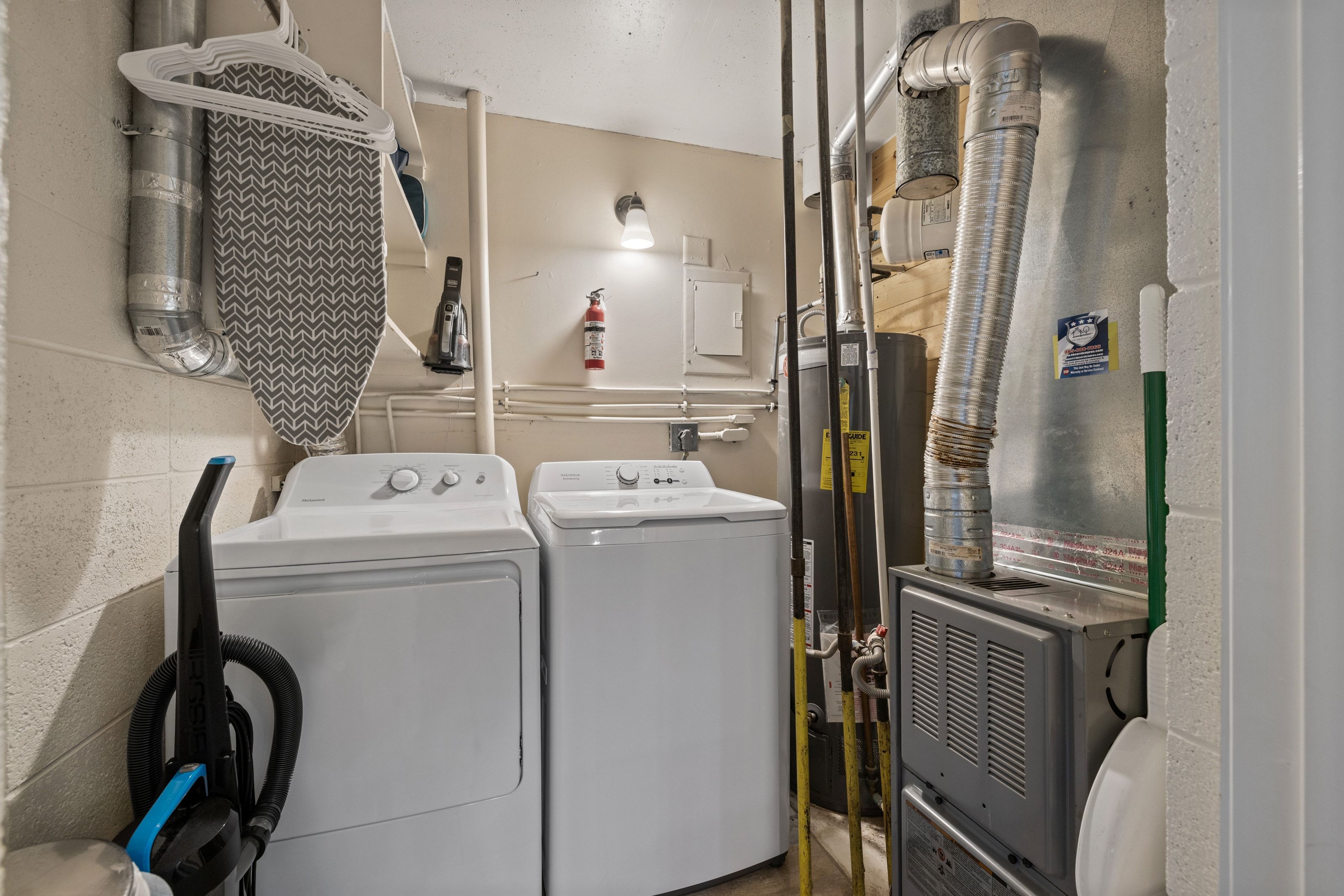 Dedicated utility space featuring a washer and dryer, exposed ductwork, wall-mounted lighting, and a water heater