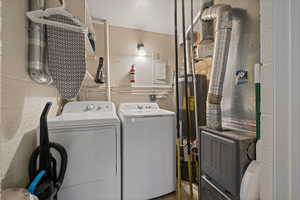 Dedicated utility space featuring a washer and dryer, exposed ductwork, wall-mounted lighting, and a water heater