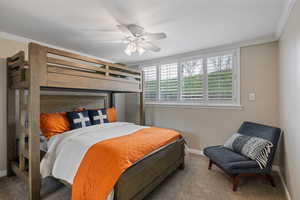 Bedroom featuring a white ceiling fan, crown molding, a window with white louvered shutters, and neutral-toned wall paint