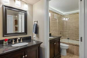 Bathroom featuring a dark wood vanity with a granite-style countertop, an undermount sink, and a framed mirror