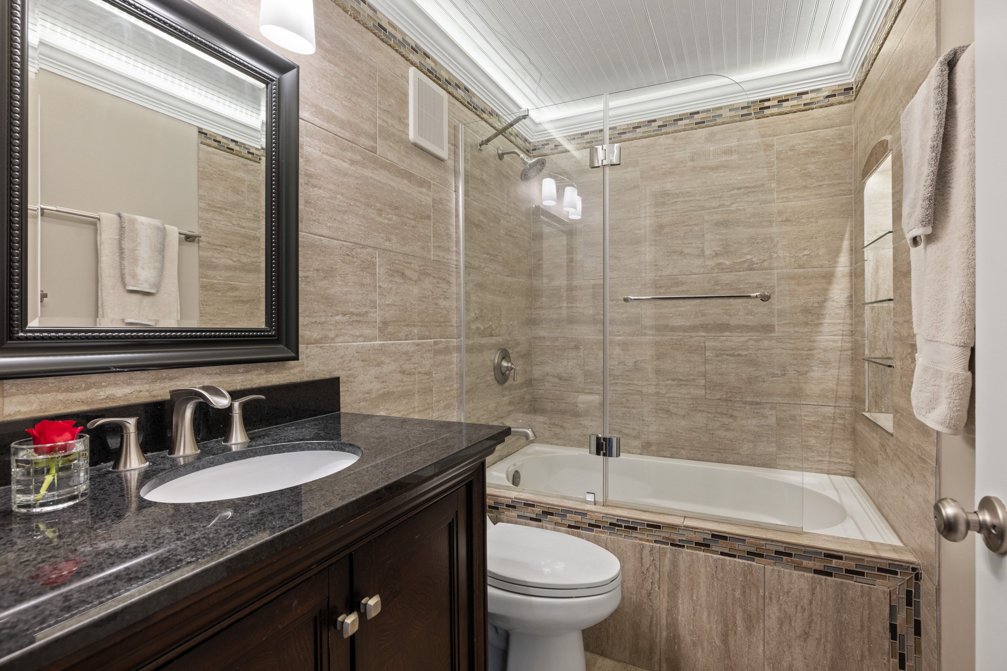 Bathroom featuring a dark wood-finish vanity with a black stone countertop, undermount sink, and brushed nickel faucet