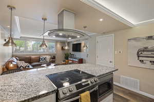 Kitchen island with a built-in electric range, integrated microwave, and speckled countertop