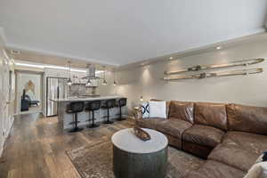 Open concept living area featuring wood-finish flooring, recessed lighting, and crown molding