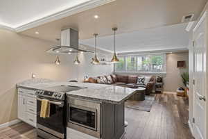 Open-concept living space featuring a kitchen island with built-in microwave and stainless steel range, granite countertops, and pendant lighting