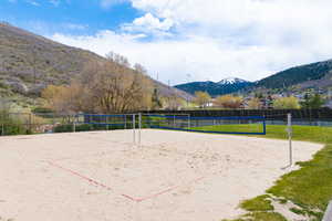 Sand volleyball court featuring a net and boundary lines, bordered by green grass
