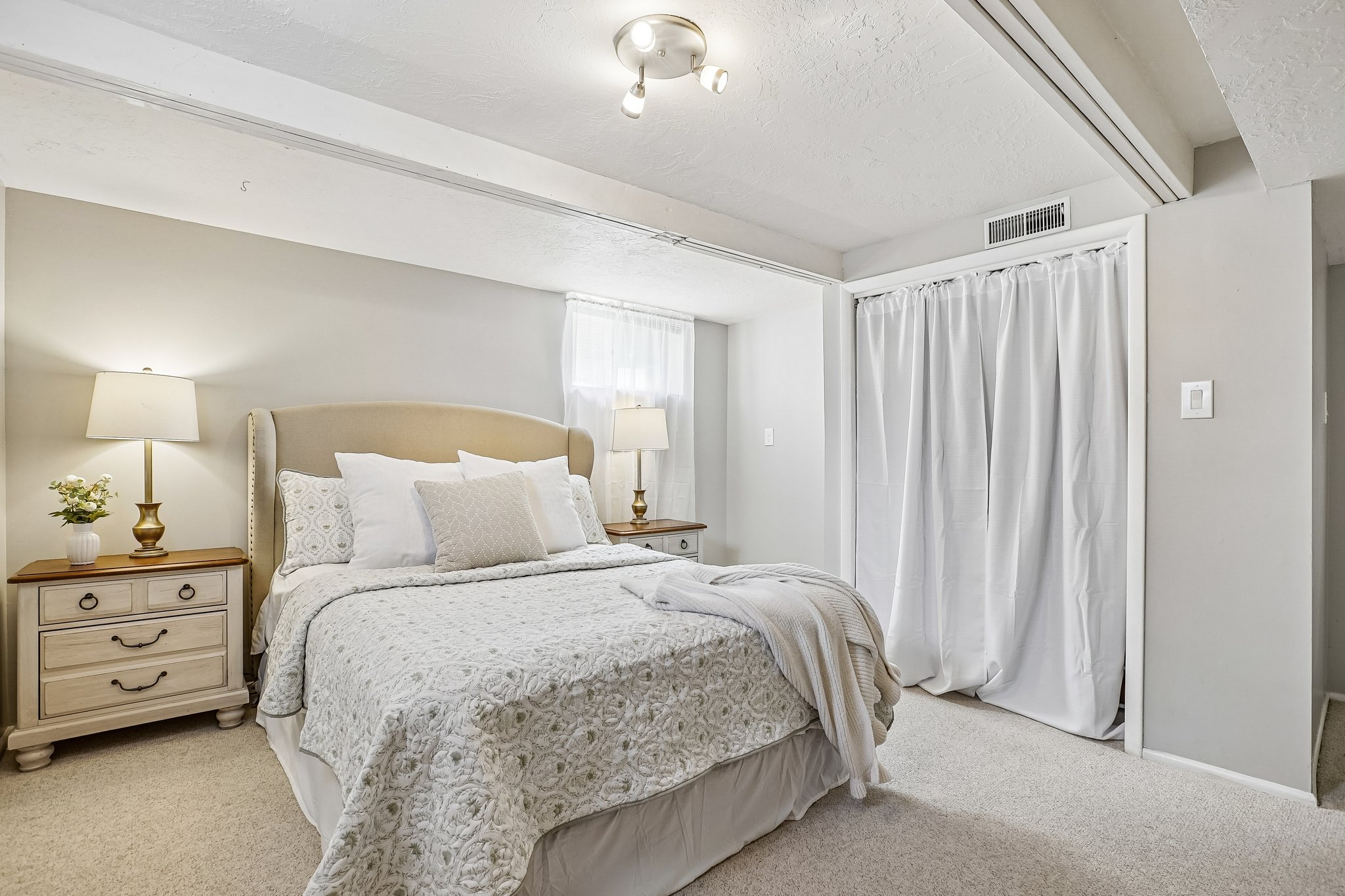 Neutral-toned bedroom featuring wall-to-wall carpeting and a ceiling-mounted light fixture