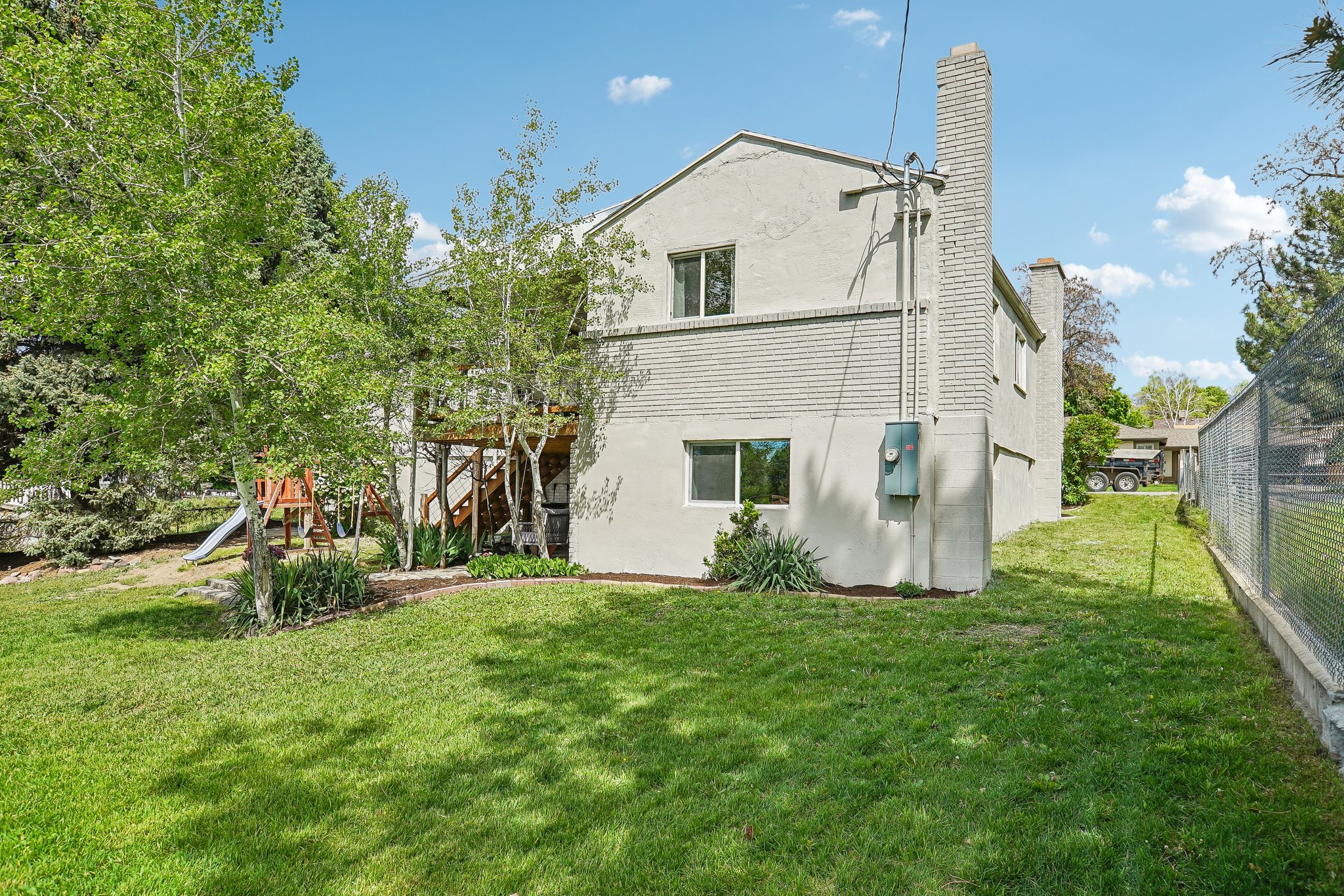 Expansive lawn area presenting the property's exterior, featuring a brick chimney and a wood-frame deck