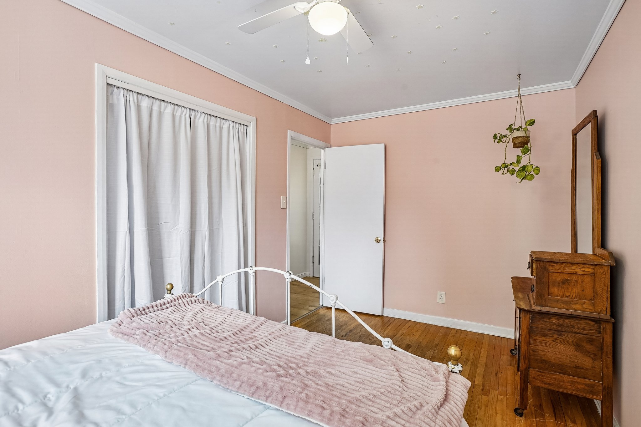 Room featuring hardwood flooring, light pink wall paint, white trim, and a ceiling fan with integrated lighting