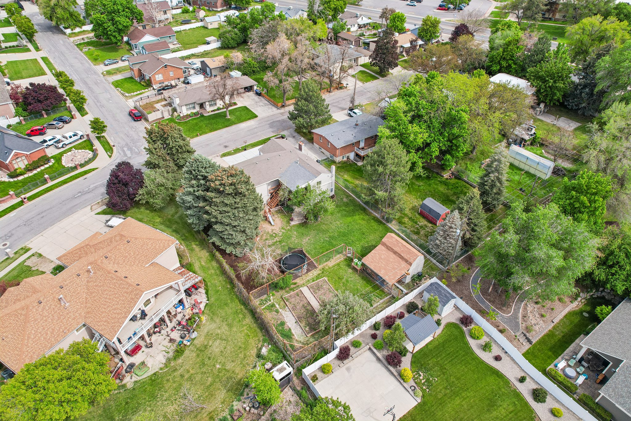 Expansive property featuring mature trees, a detached storage shed, and a fenced garden area