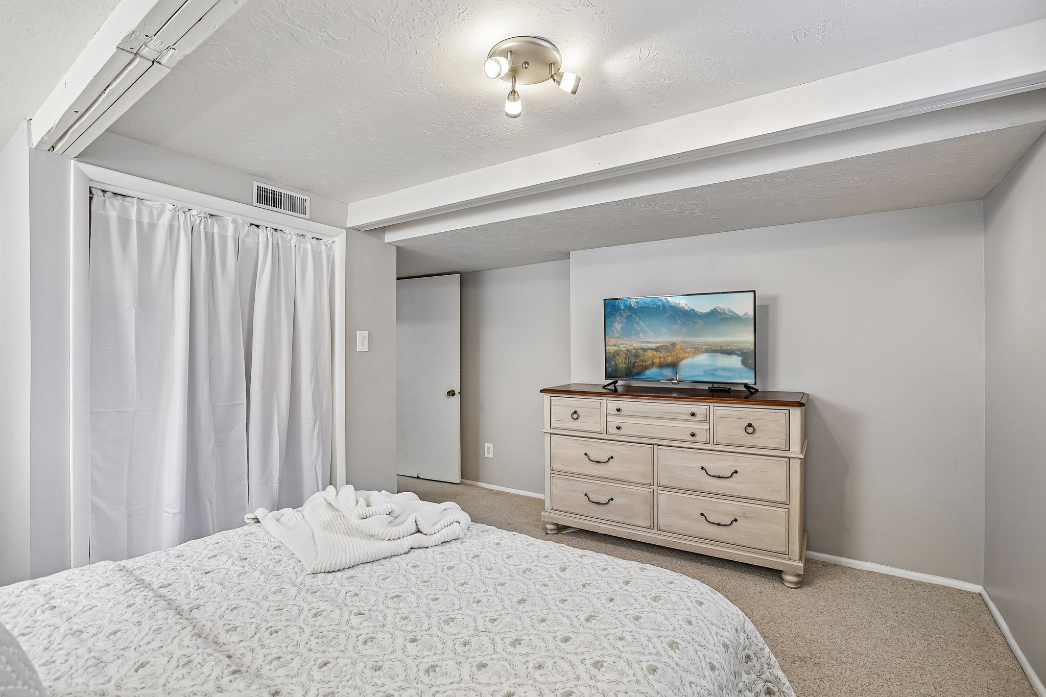 Recessed ceiling beams, neutral carpeting, and light gray wall paint create a bright interior