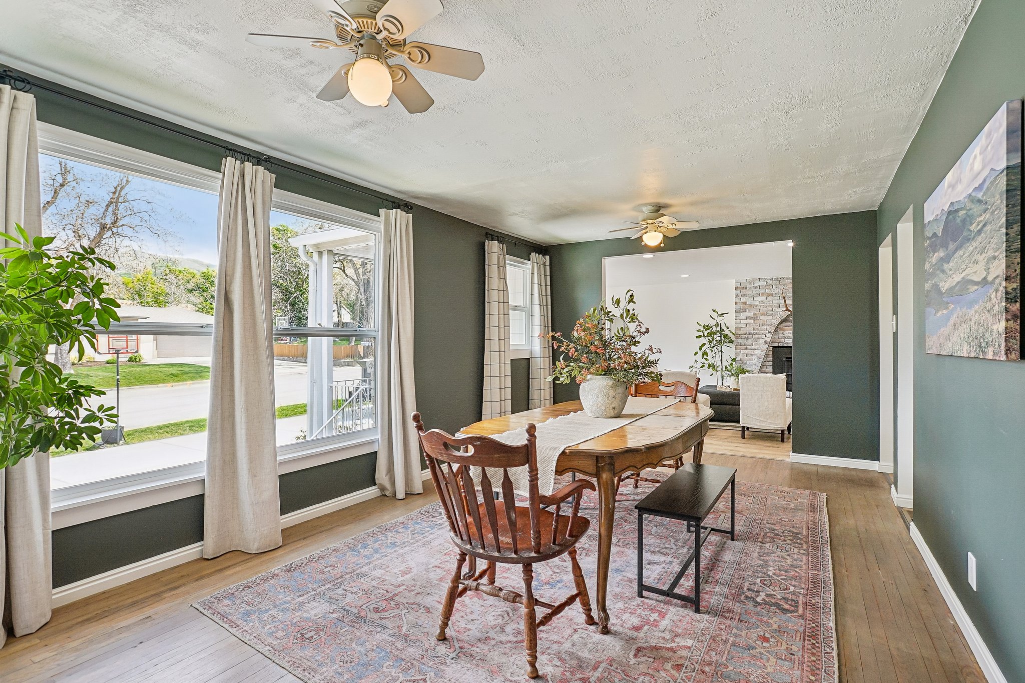 Dining area featuring wood-finish flooring, deep green walls, and large windows with white trim