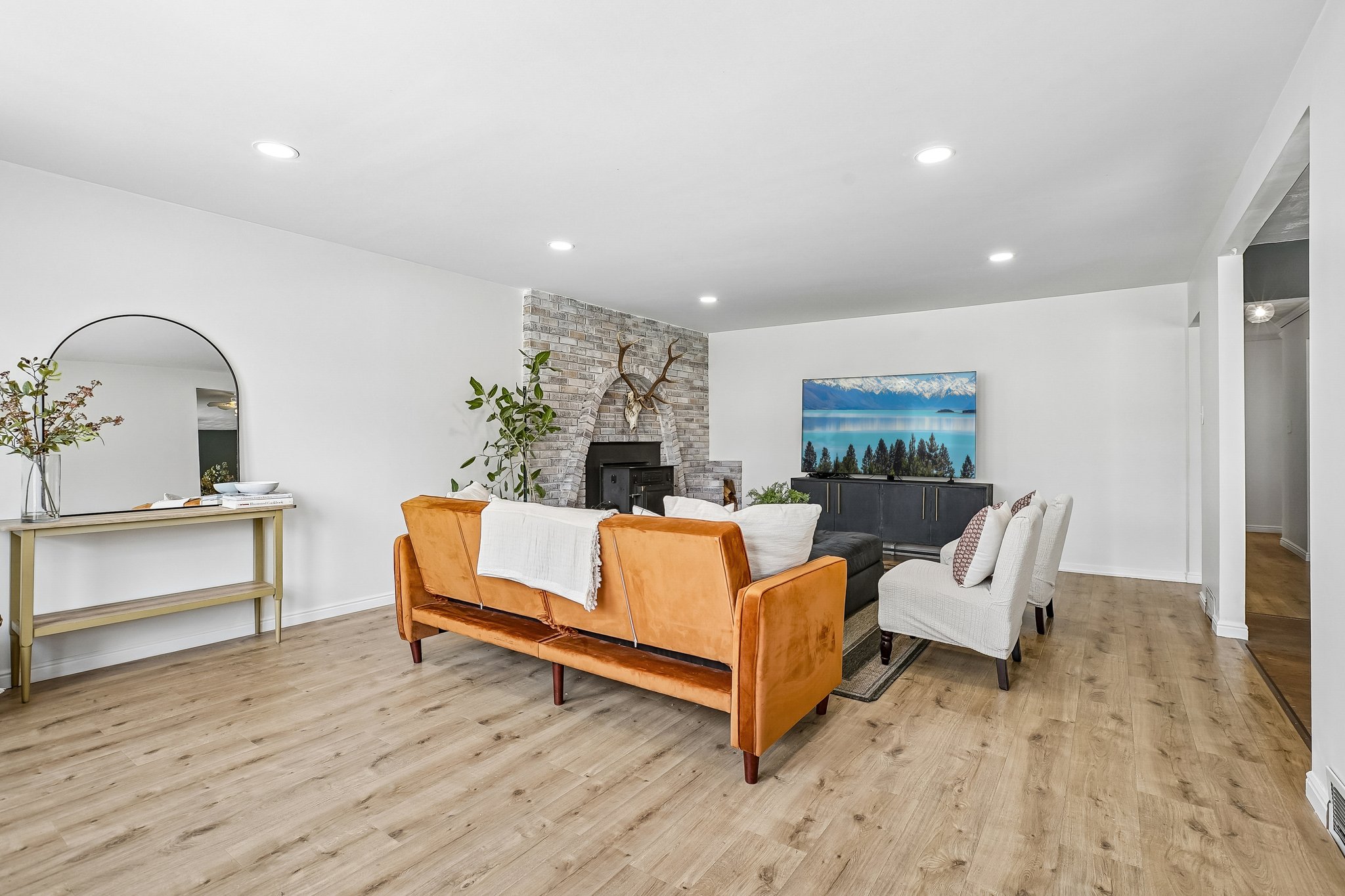Spacious living area featuring light wood-finish flooring and recessed lighting