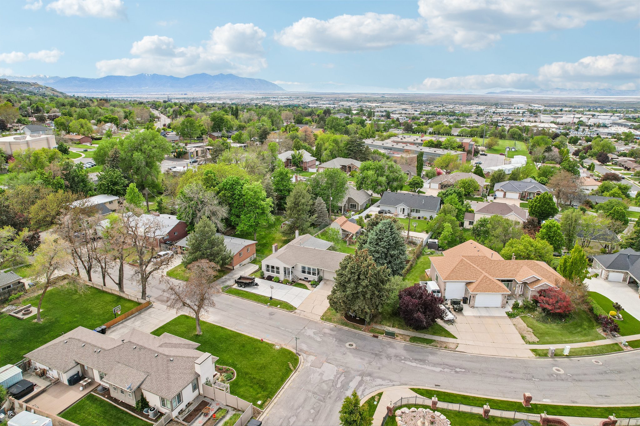 Expansive residential area featuring a diverse mix of single-family homes with mature landscaping, paved streets, and mountain scenery