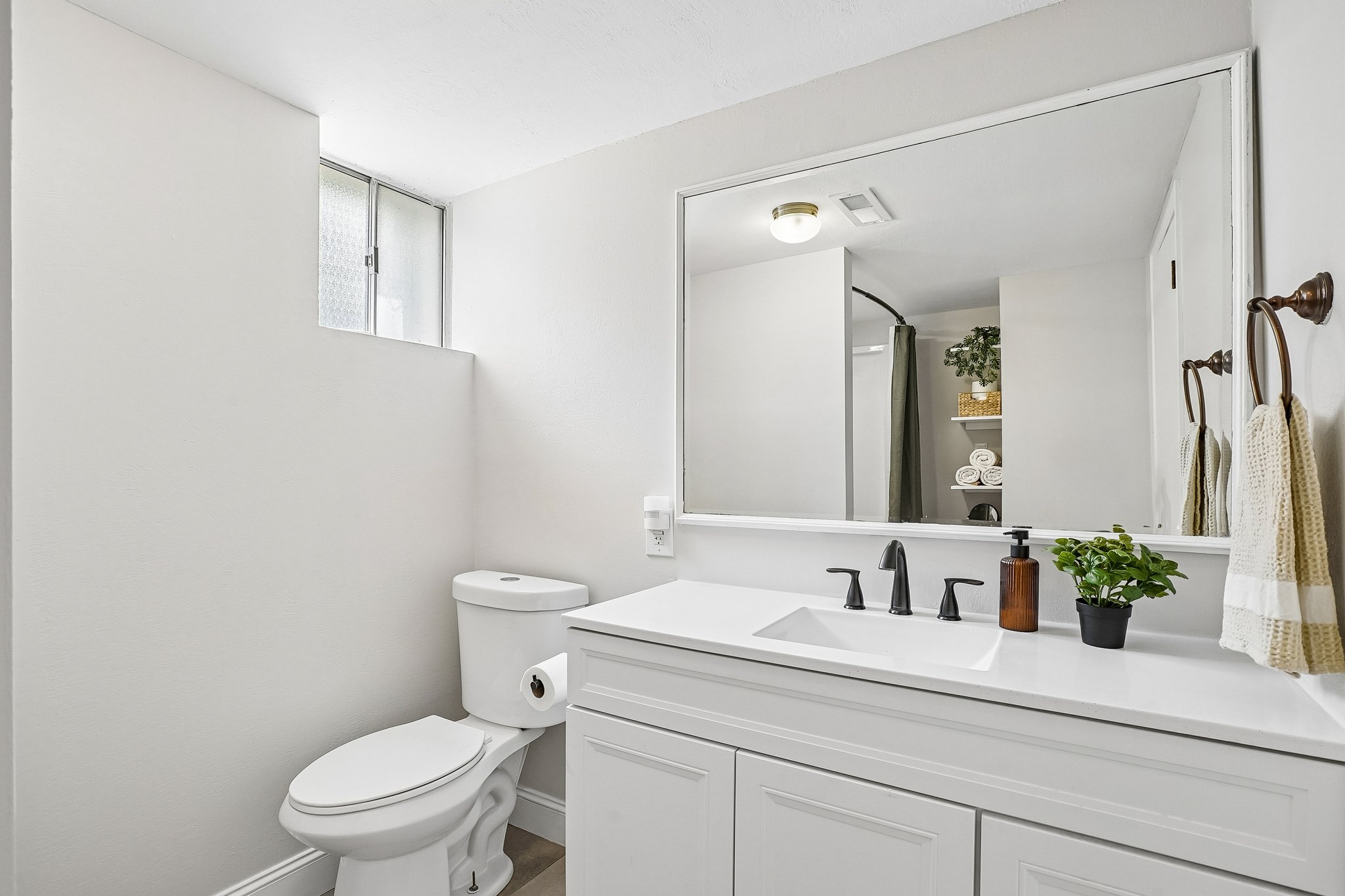 Bathroom vanity featuring a single basin, solid surface countertop, matte black faucet, and white cabinetry