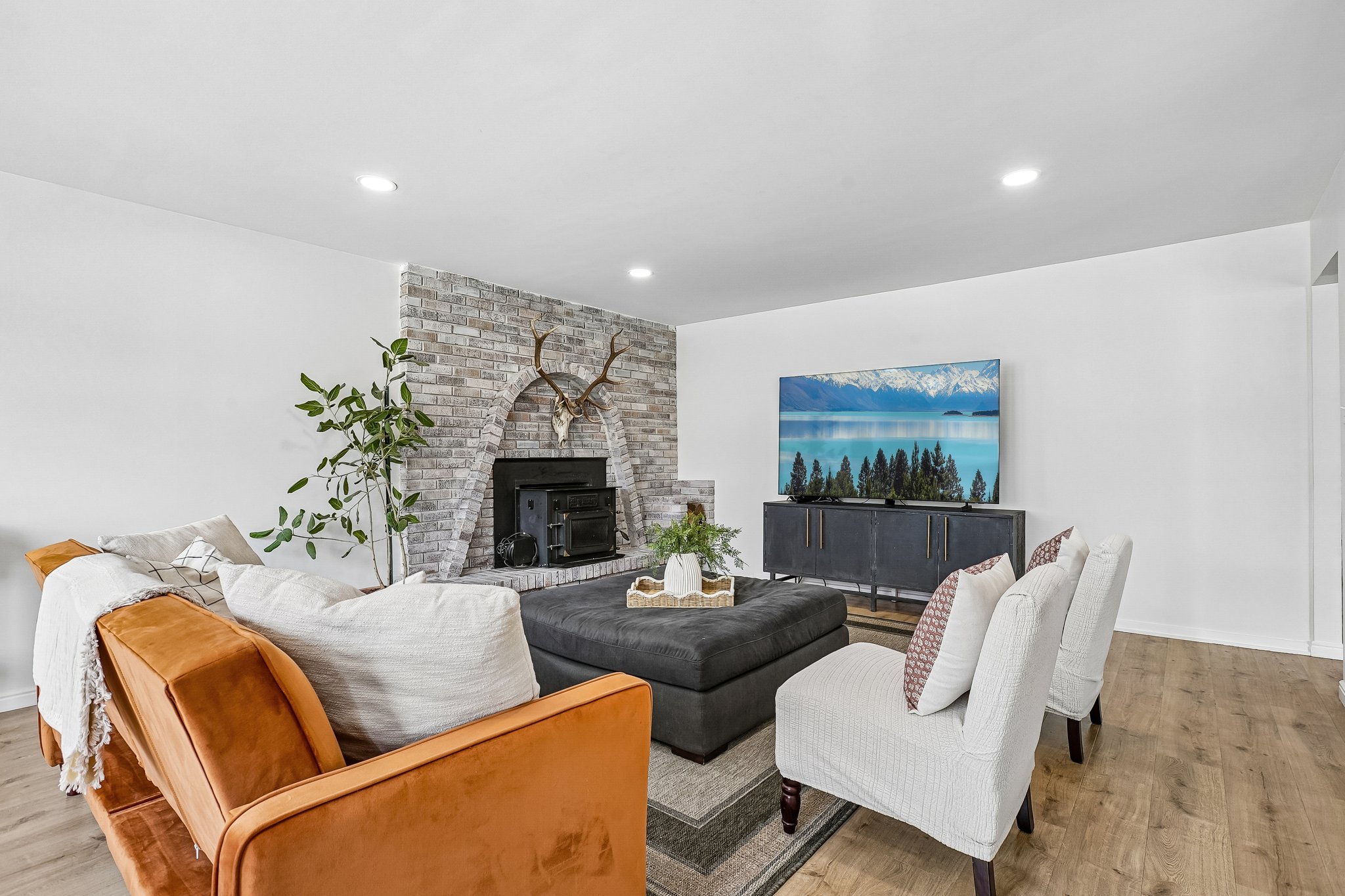 Living area featuring a brick-surround fireplace with hearth, wood-finish flooring, and recessed ceiling lighting