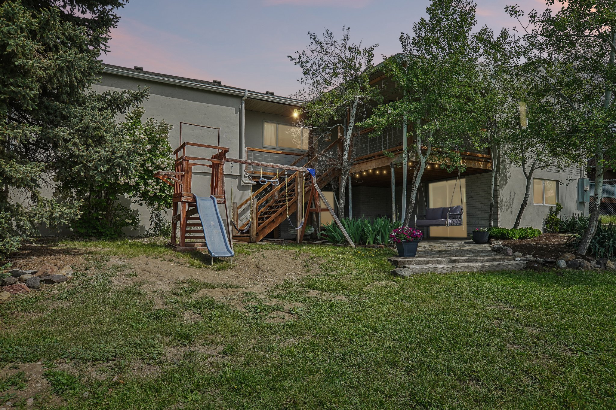 Expansive backyard featuring a multi-level deck, string lighting, and mature trees