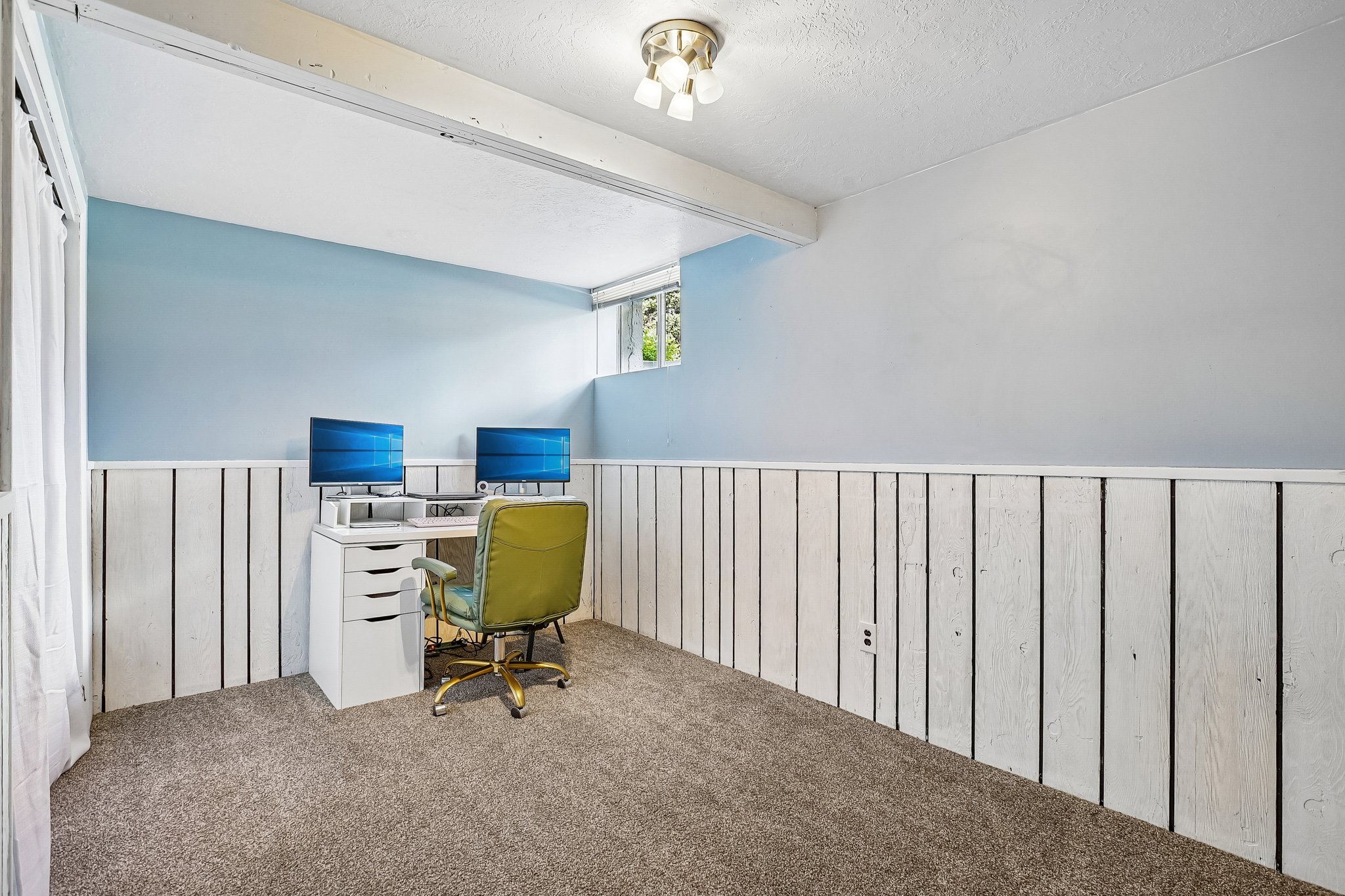 Carpeted room featuring light blue walls above white wood paneling