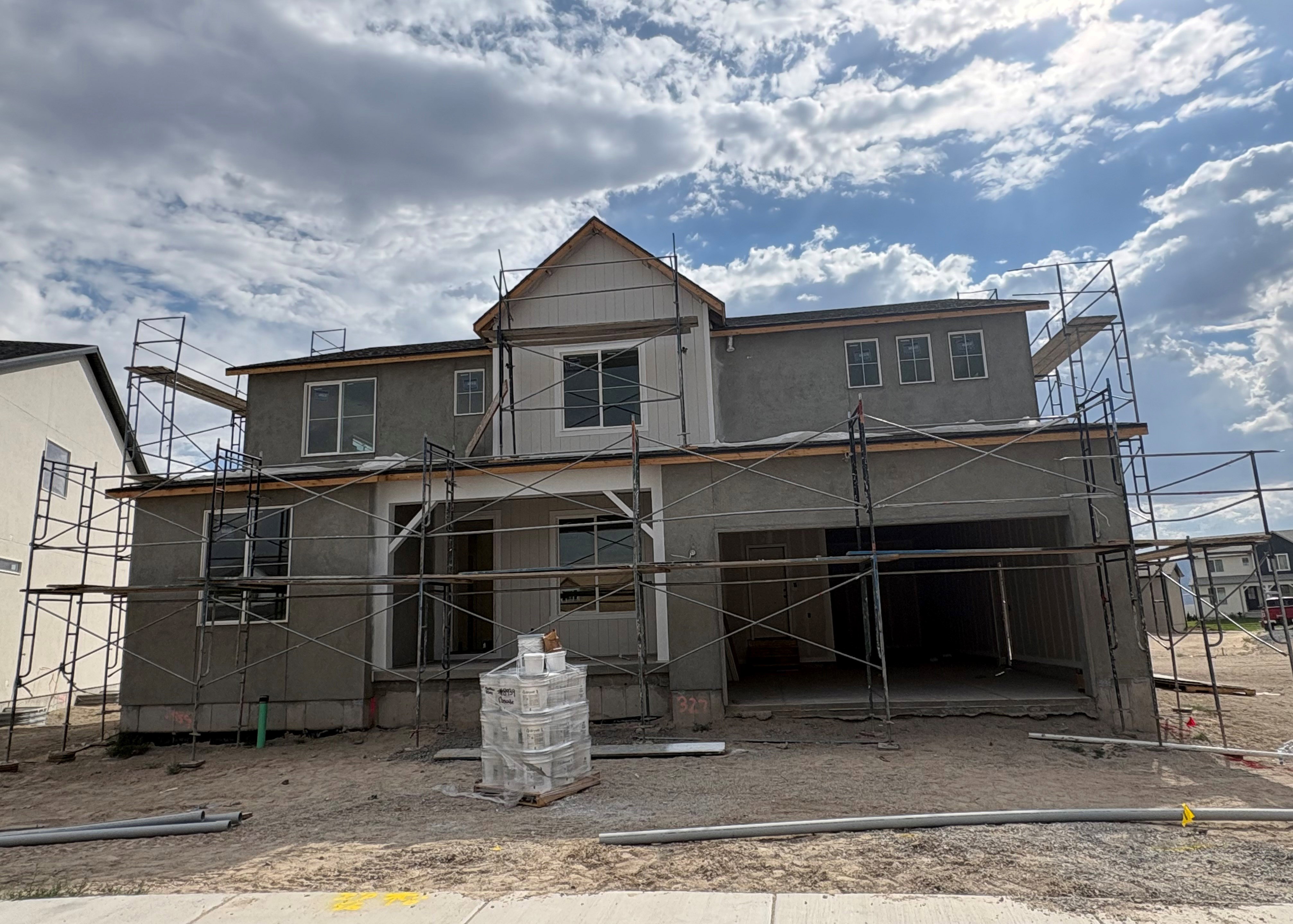 Two-story stucco and siding exterior with an attached three-car garage (tandem)