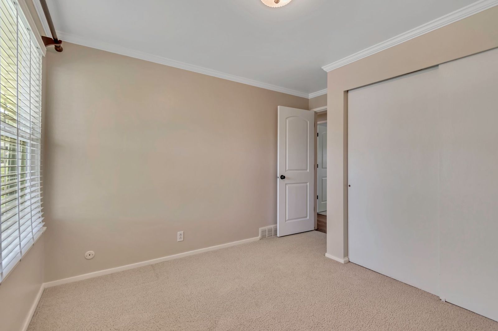 Neutral-toned interior with light carpet flooring, crown molding, and white trim