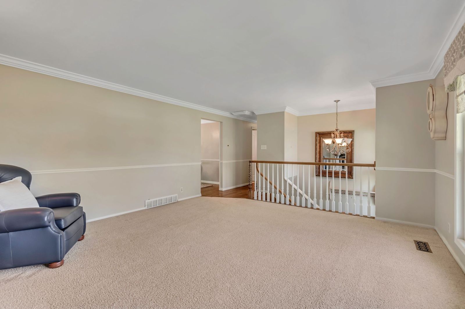 Spacious room featuring neutral carpeting, two-tone painted walls, and white crown molding