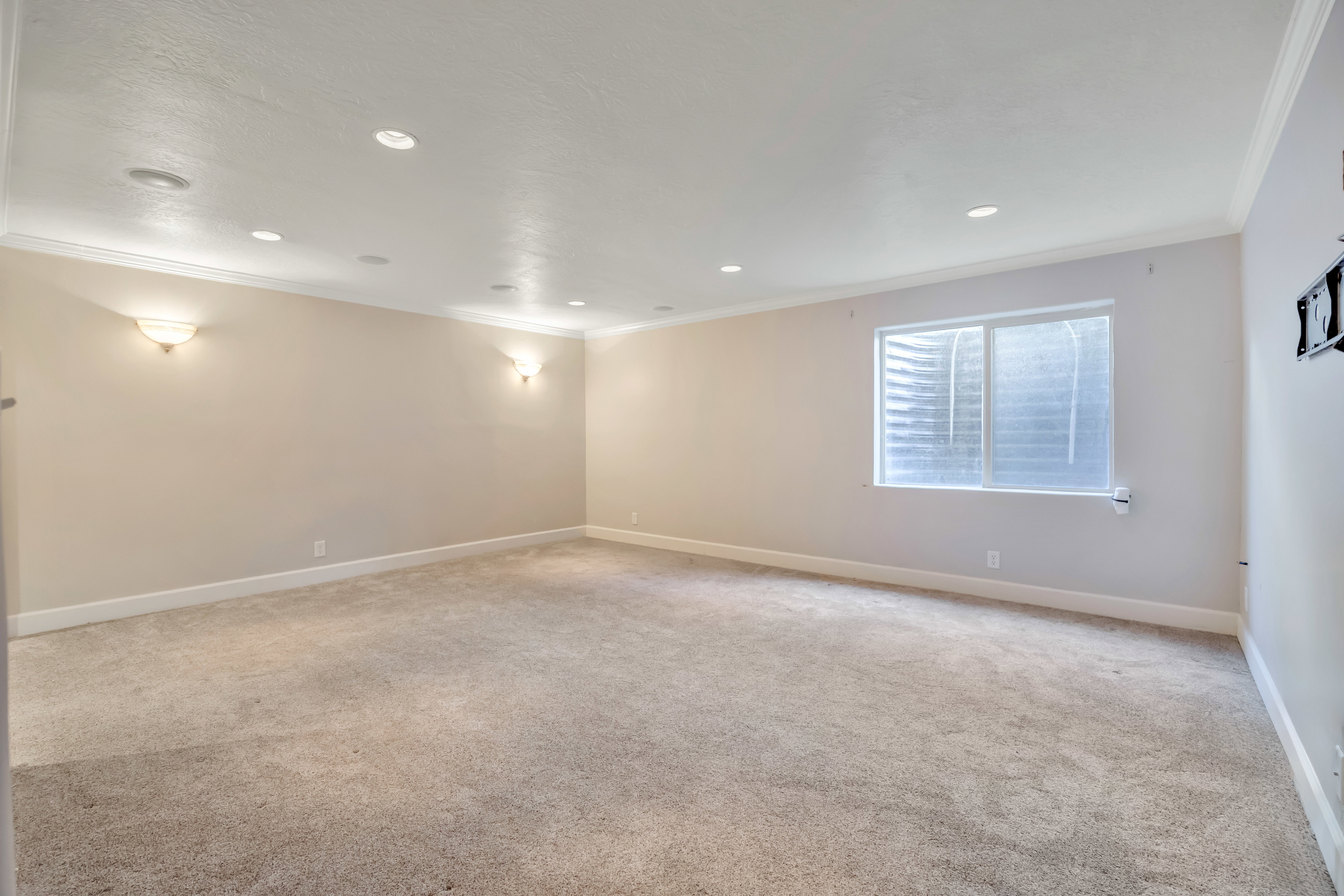 Spacious room featuring neutral carpeting, light-toned walls, recessed lighting, and crown molding