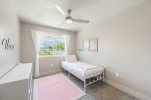Bedroom featuring a window with exterior views, ceiling fan, and carpet flooring