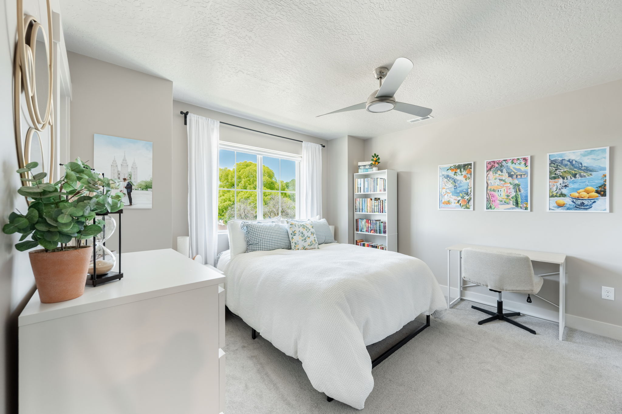 Bedroom featuring carpet flooring, a multi-pane window with white blinds and drapes, a ceiling fan, and a built-in shelving unit