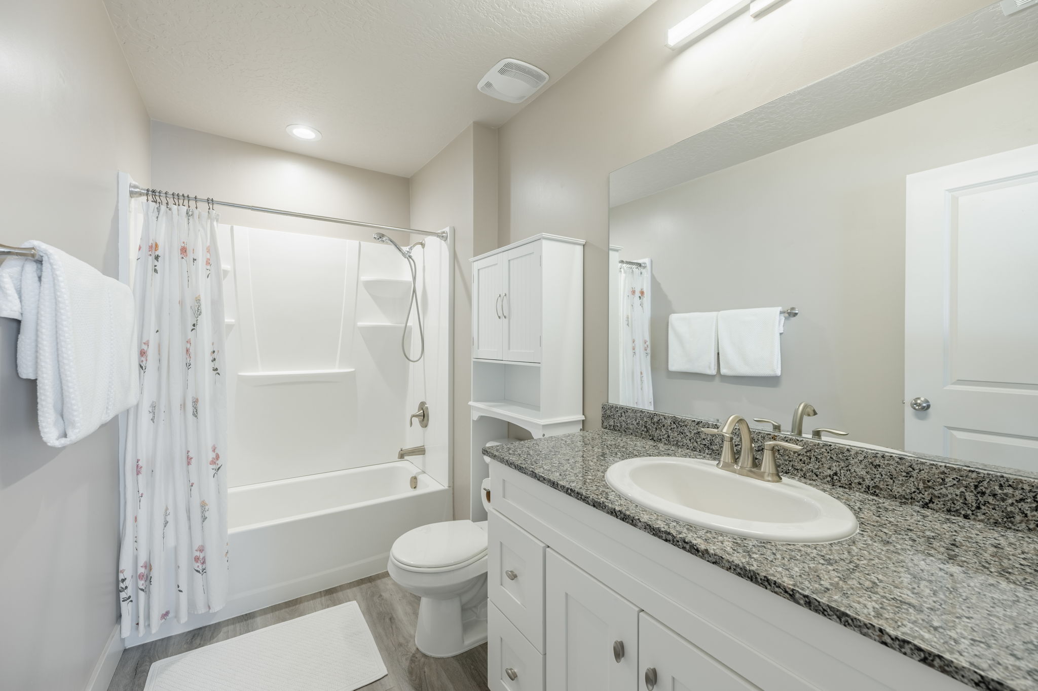 Bathroom featuring a vanity with a granite countertop, undermount sink, and brushed nickel faucet