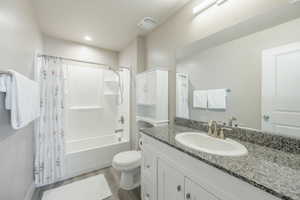 Bathroom featuring a vanity with a granite countertop, undermount sink, and brushed nickel faucet