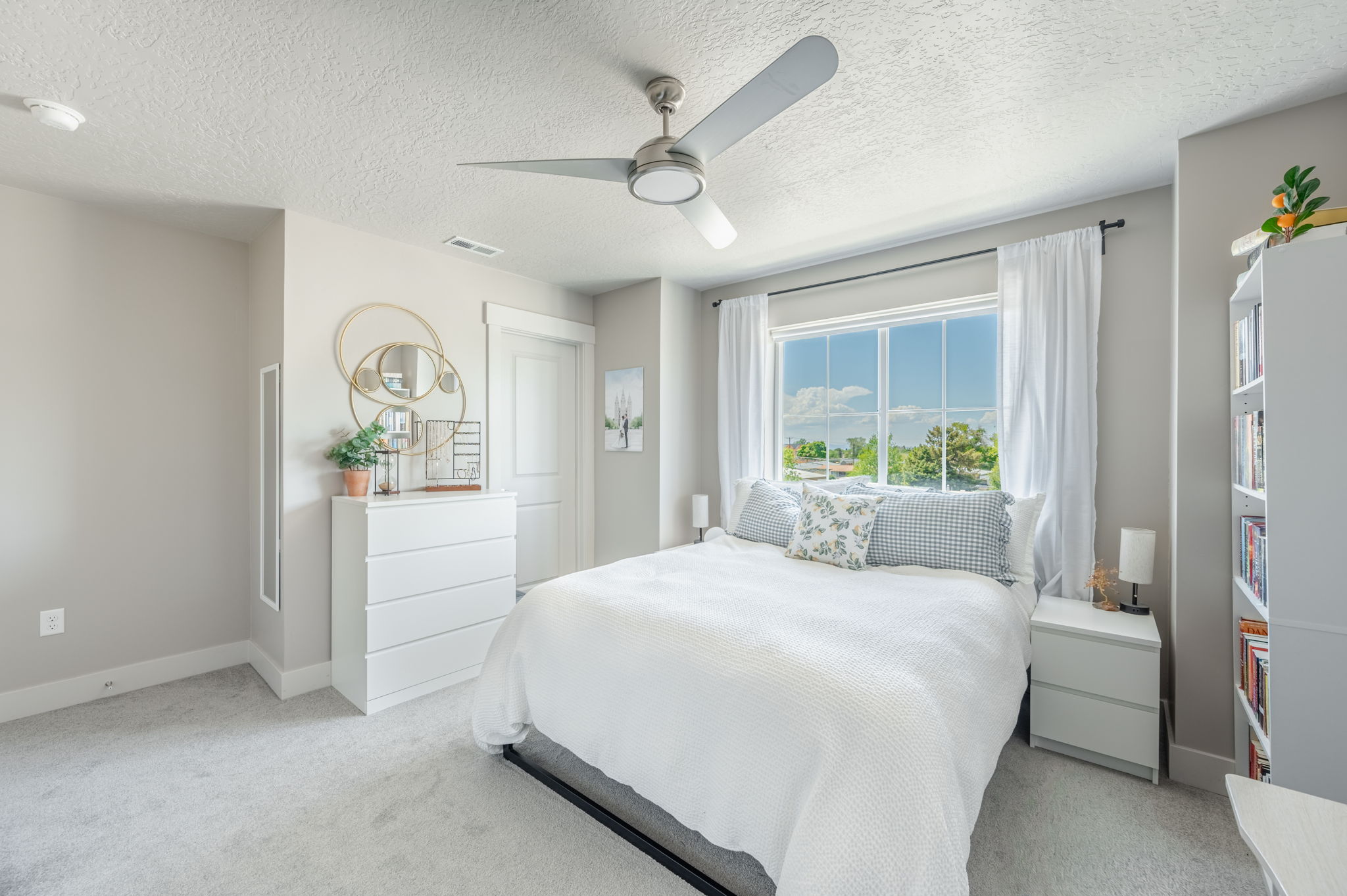 Bright room featuring a large multi-pane window, light-colored carpeting, and a ceiling fan with integrated lighting
