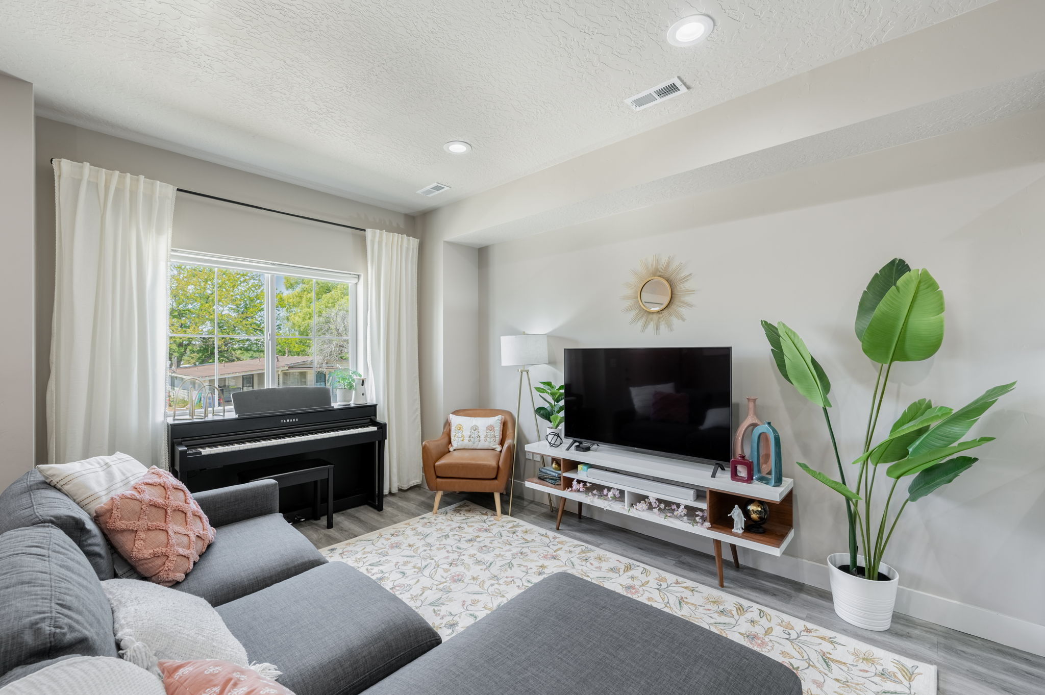 Living area featuring wood-finish flooring, recessed lighting, and a large window with white curtain panels