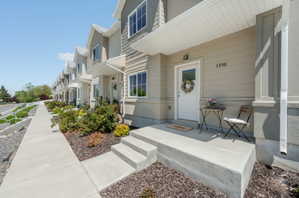 Exterior featuring light neutral siding, white trim, and a covered entry porch