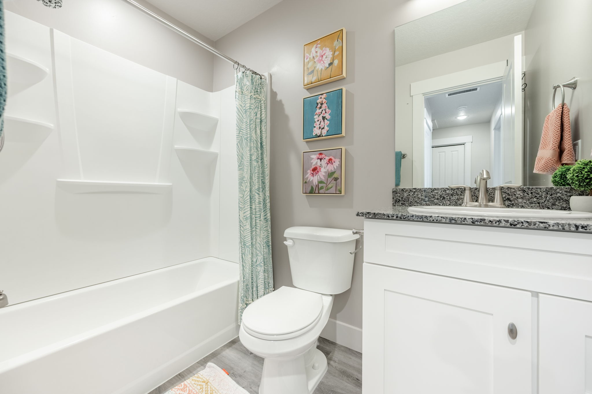 Bathroom featuring a white bathtub and shower surround, a toilet, and a vanity with a dark speckled countertop