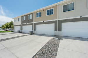 Townhome exterior featuring individual garage access and a dedicated concrete parking pad