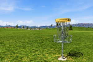 Expansive grassy area featuring a disc golf basket, rolling hills, and distant mountains