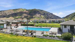 Outdoor swimming pool with integrated spa, surrounded by a paved patio and black metal fencing