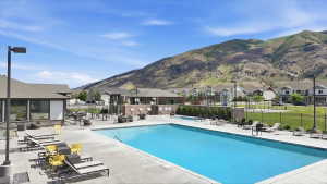 Community swimming pool with surrounding concrete decking, lounge seating, and mountain scenery