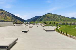 Expansive concrete skatepark with multiple ramps and features, bordered by a manicured green lawn