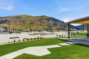 Expansive green space featuring a concrete pathway, a covered patio area with picnic tables, and a large skate park