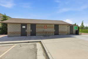 Commercial building featuring concrete block construction with a shingled roof, multiple entry points, and a built-in water fountain