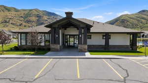 Contemporary building exterior with a prominent entry, stone accents, and a dark shingle roof