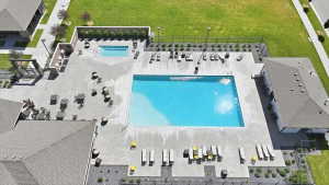 Expansive outdoor recreational area featuring a large swimming pool, a separate hot tub, concrete decking, and surrounding landscaping
