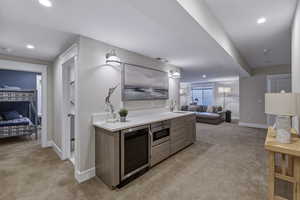Built-in wet bar featuring a beverage refrigerator, microwave, and sink, complemented by recessed and wall sconce lighting