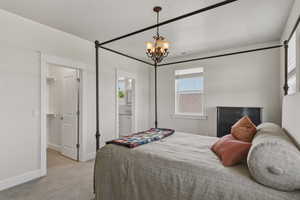 Spacious bedroom featuring light neutral wall tones, plush gray carpeting, and a traditional chandelier