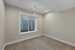 Carpeted room featuring a white-trimmed window, a decorative chandelier, recessed lighting, and neutral wall tones with white baseboards