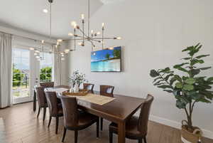 Vaulted ceiling with dual modern Sputnik-style chandeliers over wood-finish flooring