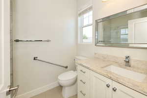 Bathroom featuring a single vanity with stone countertop, integrated sink, and chrome faucet
