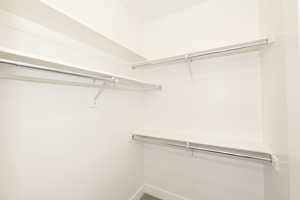 Walk-in closet featuring multiple white shelving units and chrome hanging rods