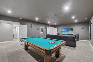 Recreation room featuring a wood-finish pool table with a turquoise felt surface, recessed lighting, and grey carpeting