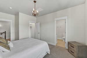 Carpeted bedroom featuring a decorative chandelier and a built-in closet with shelving